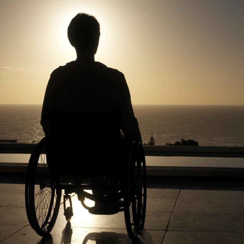 silhouette of man sitting on wheelchair watching sunset contemplating his life, donate to help him